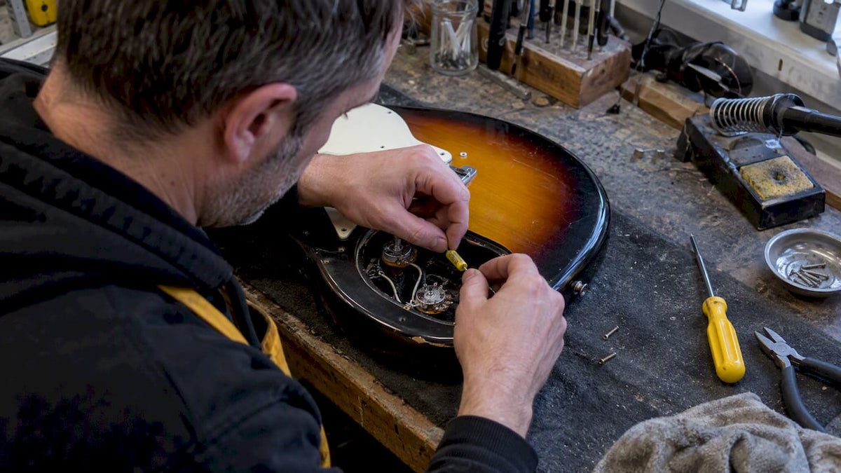 Technician rewiring an electric guitar tone pot