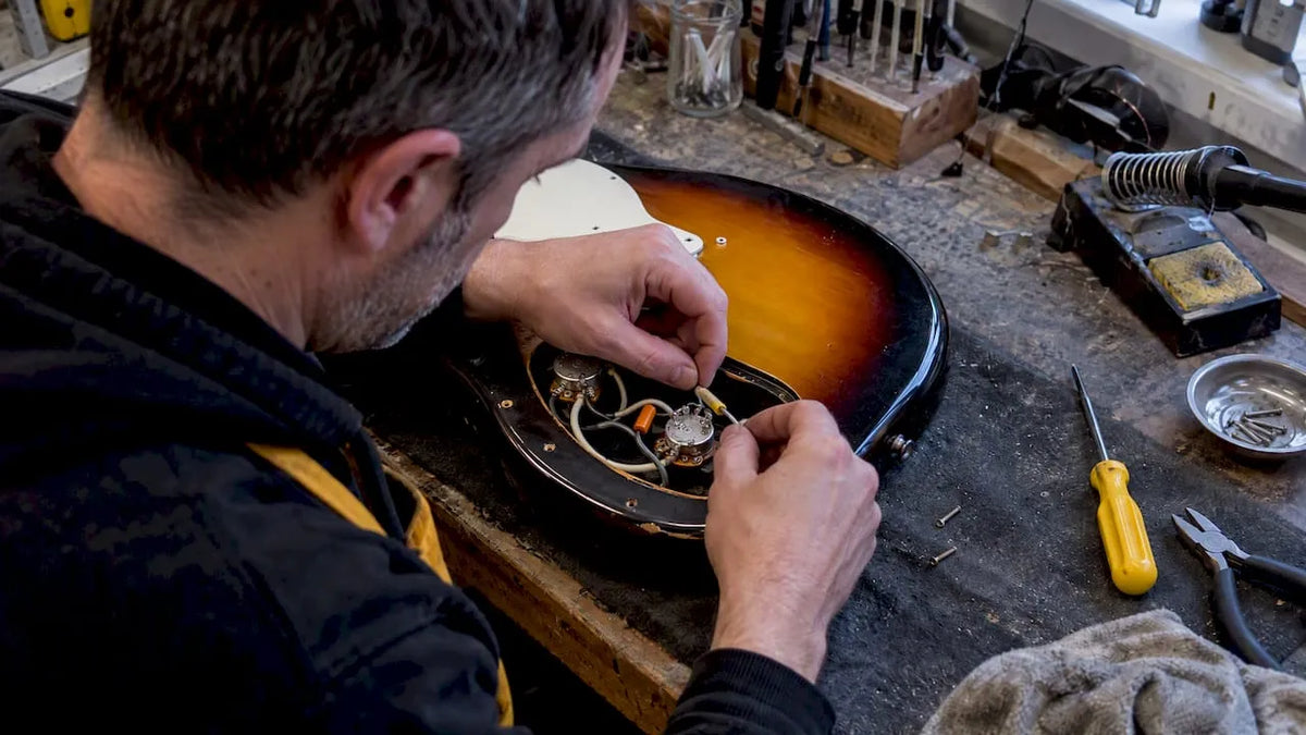 Technician rewiring an electric guitar tone pot