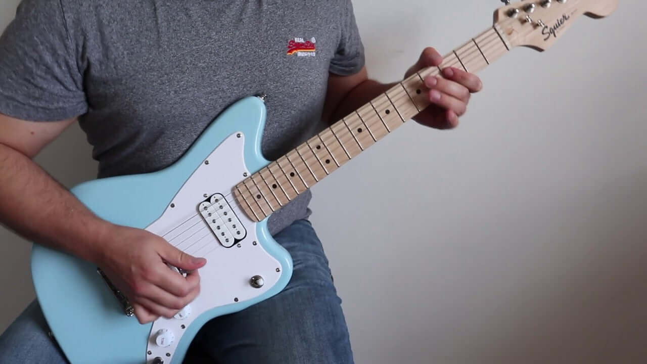 Person playing a blue 3/4 size electric guitar, ideal for kids and beginners at MusicStreet.