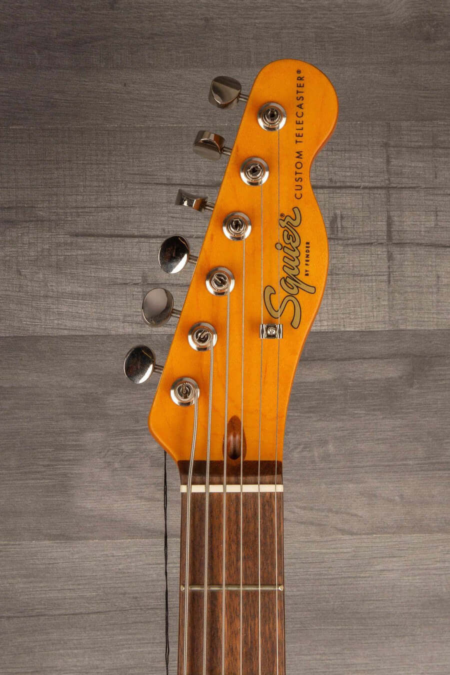 Squier Classic Vibe Baritone Custom Telecaster guitar headstock with strings and tuning pegs.