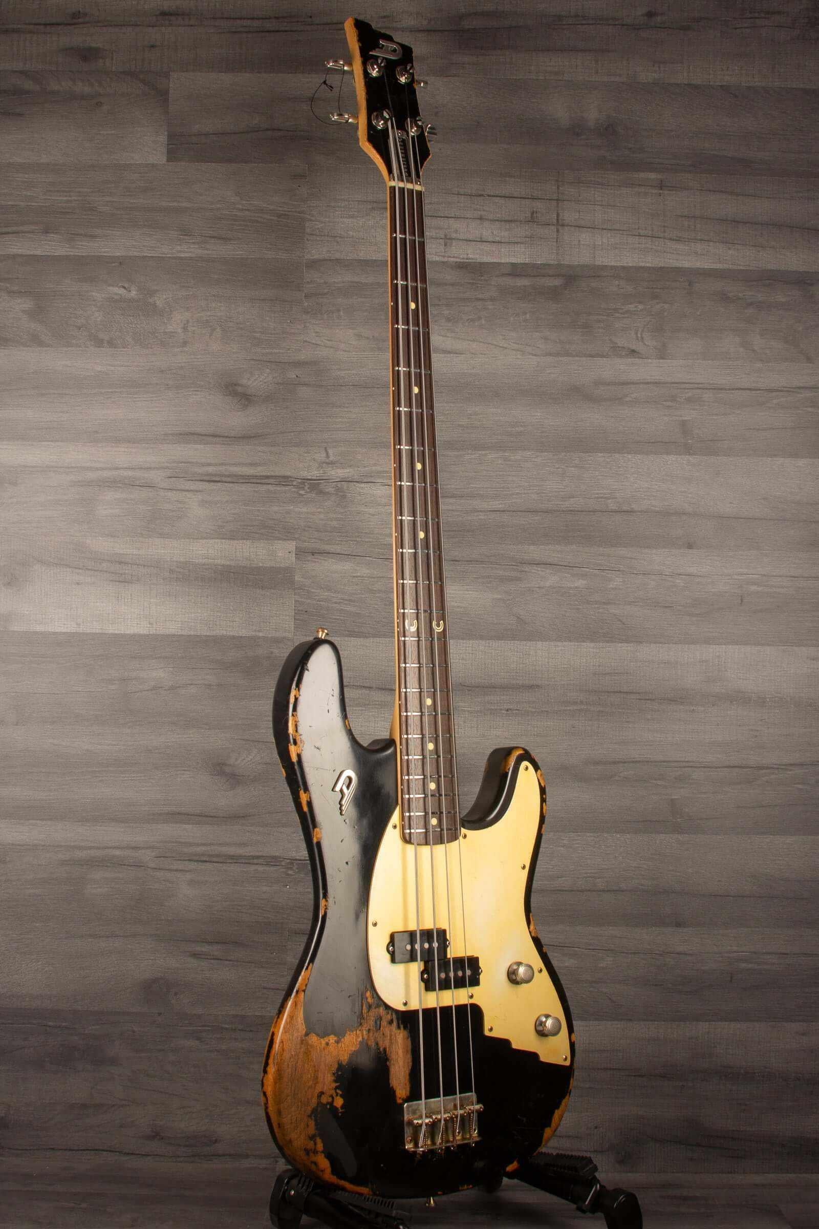 Duesenberg Chris Chaney Bass Black Distressed LTD showcased against a wood backdrop, featuring a solid Alder body and a vintage finish.