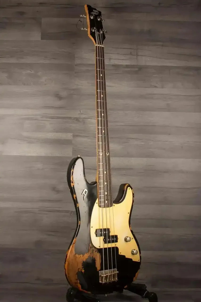 Duesenberg Chris Chaney Bass Black Distressed LTD showcased against a wood backdrop, featuring a solid Alder body and a vintage finish.