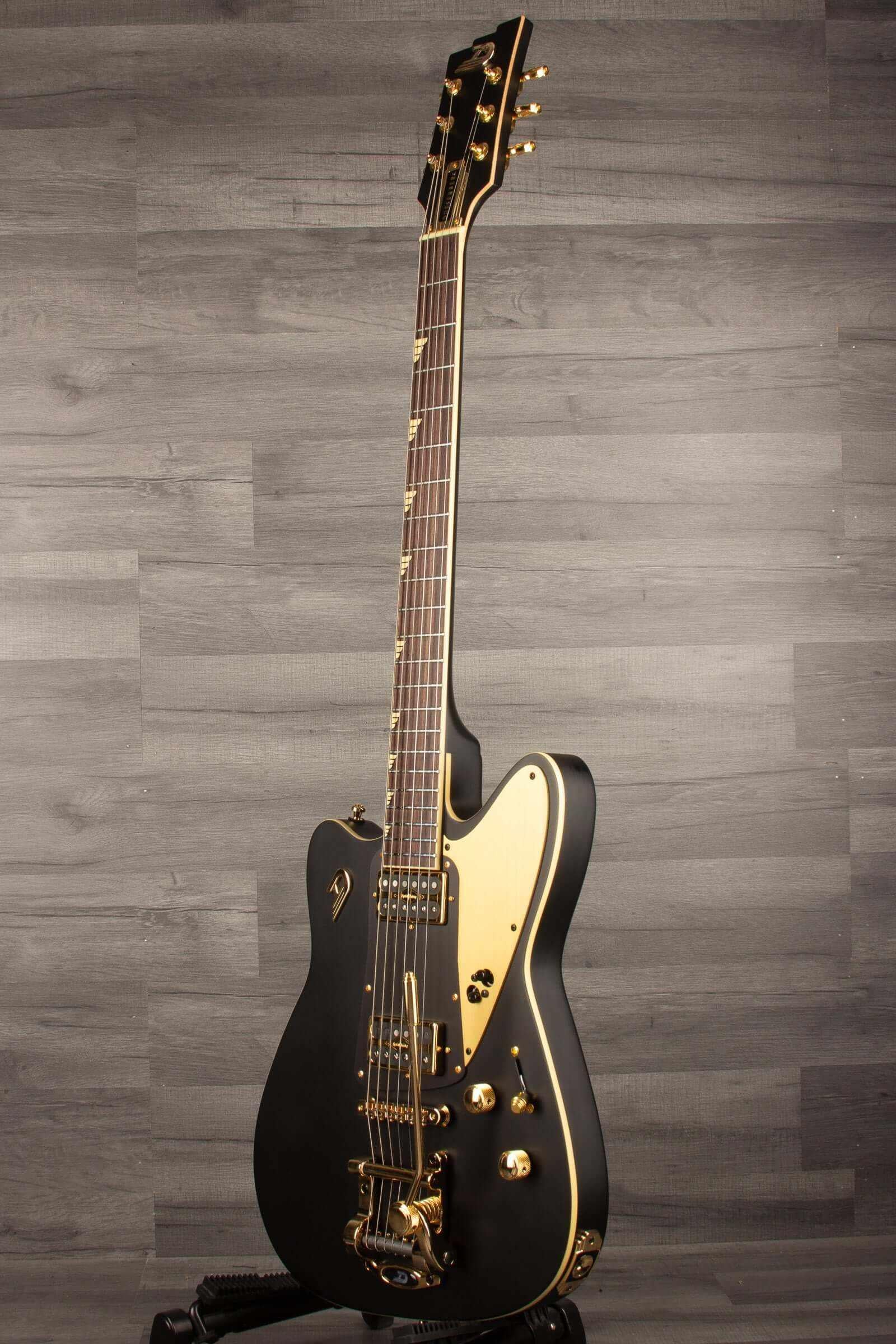 Duesenberg Falken Tremola , Electric Guitar - Matte Black showcased against a dark wood backdrop.