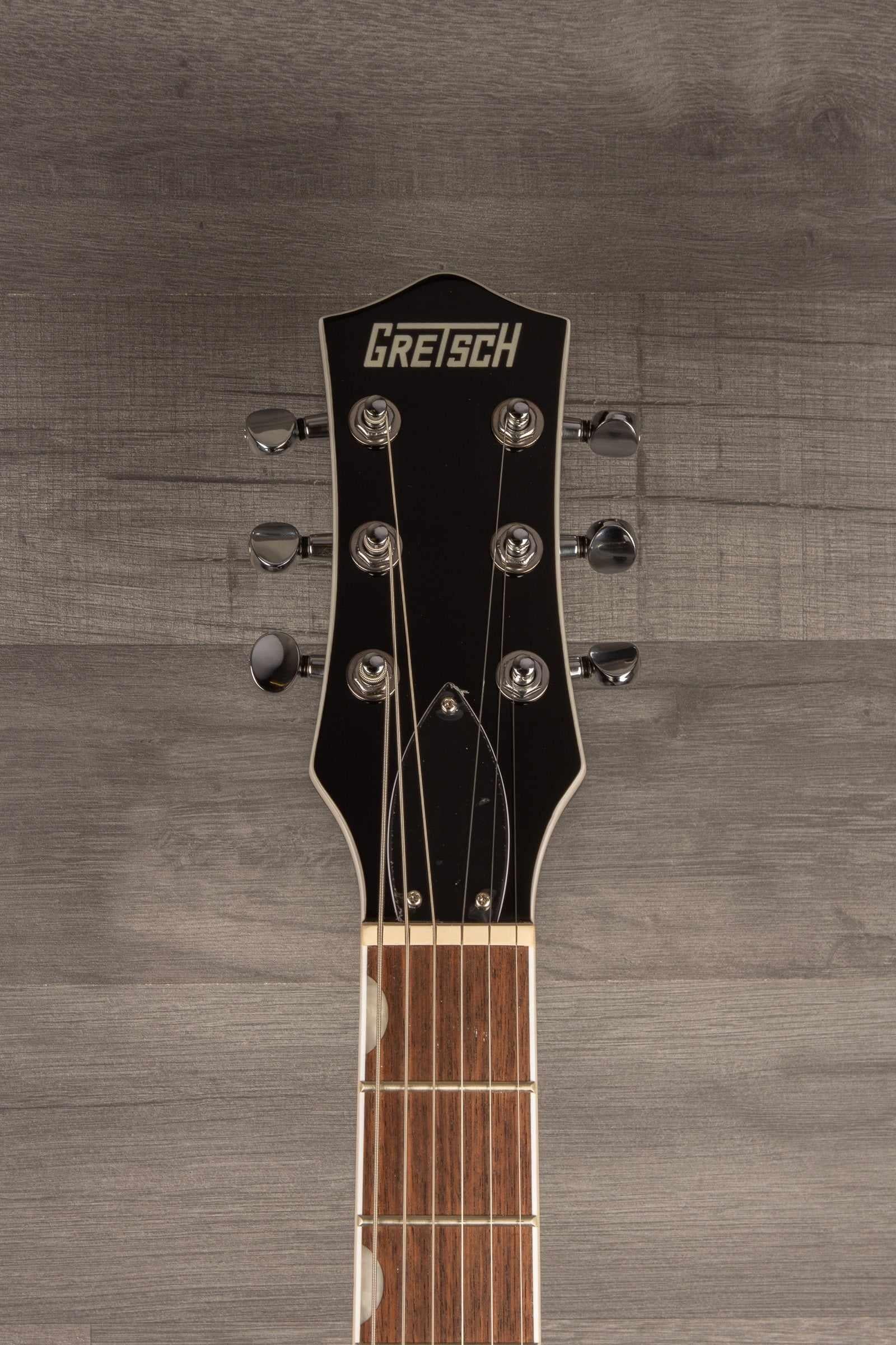 Gretsch G5230T Electromatic Sparkle Jet guitar headstock with tuning pegs and logo on a wooden background.