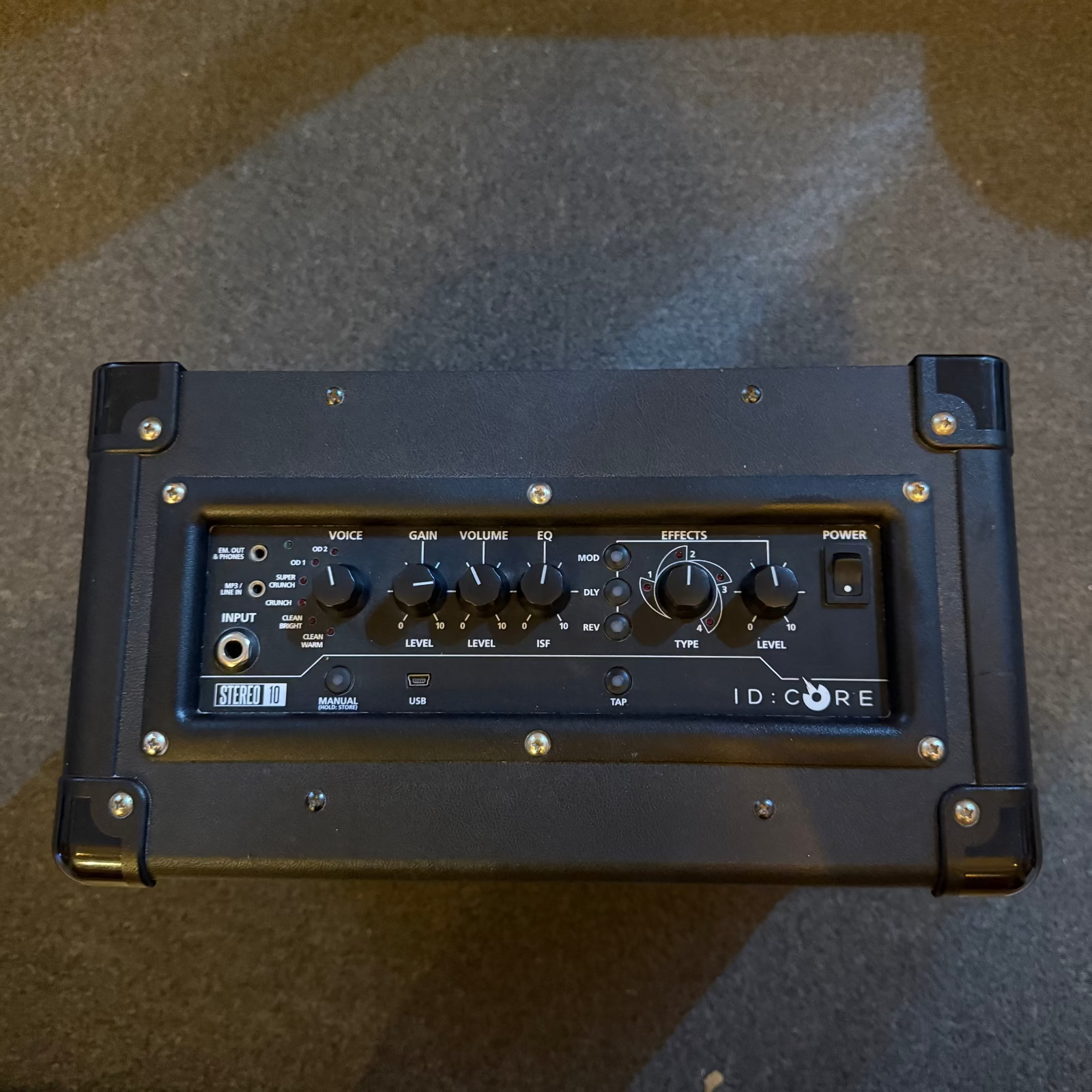 A black ID Core 10 portable guitar amplifier photographed from above on a dark carpeted floor.