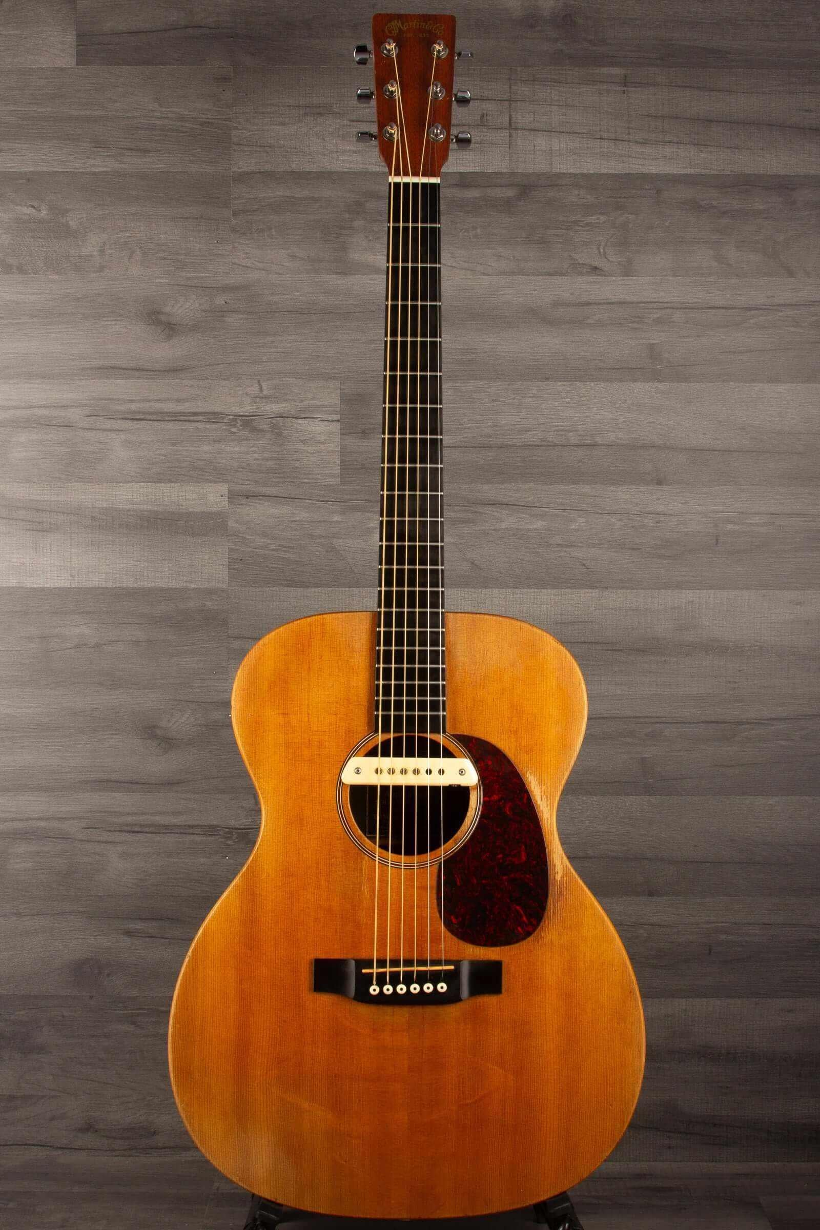 USED - Martin 000X1 inc LR Baggs M1 & hard case displayed on a stand against a gray background.