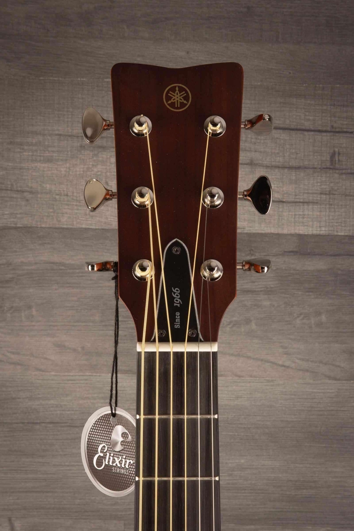 Yamaha FSX3 II guitar headstock with tuning pegs and Elixir tag on a wooden background.