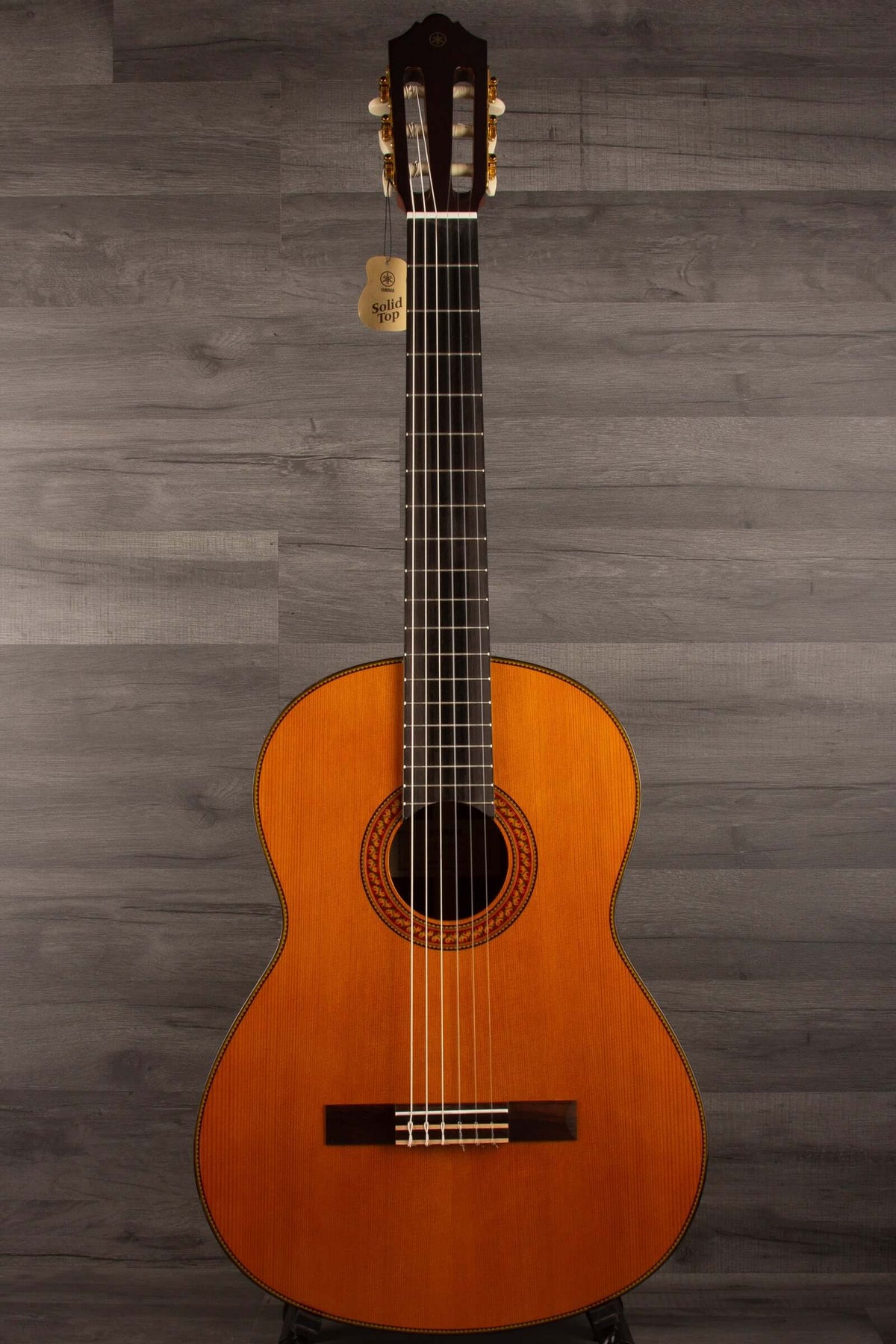 Yamaha CG192C classical guitar with a beautiful body design and a rich, warm finish on a gray background.