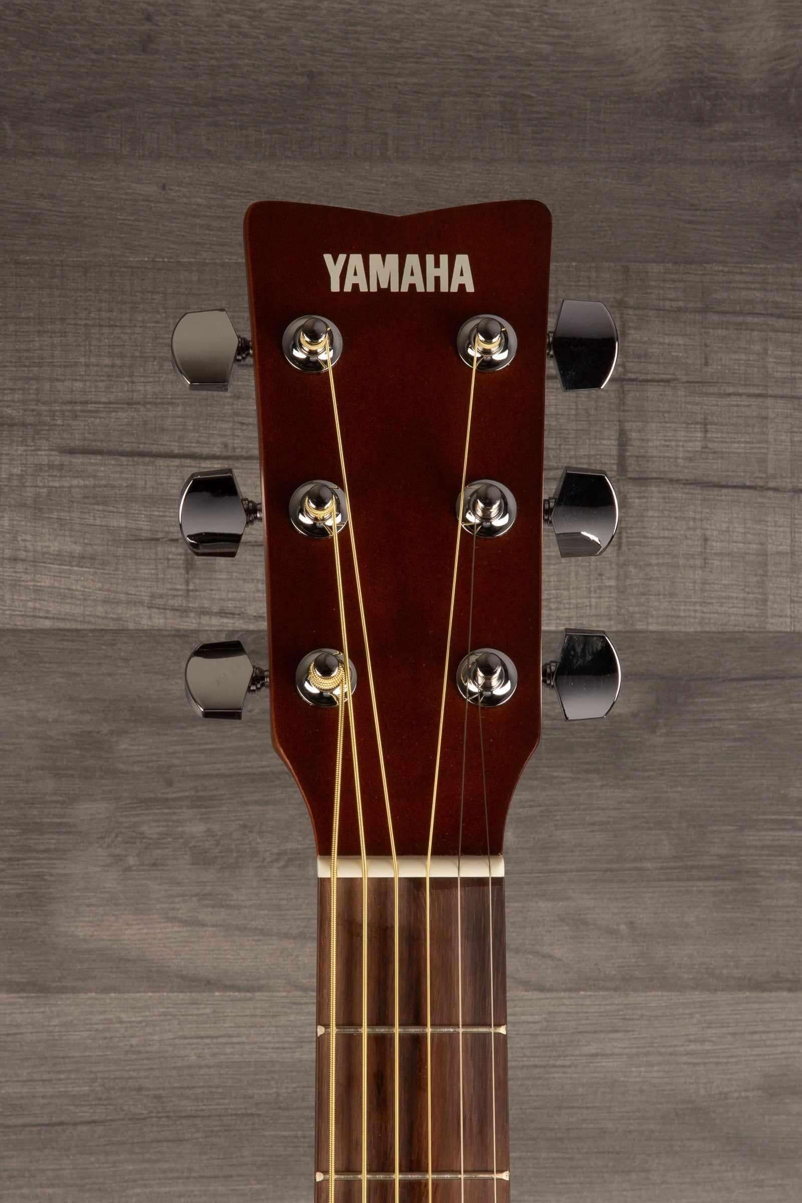 Yamaha FS400 Natural Satin acoustic guitar headstock with tuning pegs and strings against a wooden background.