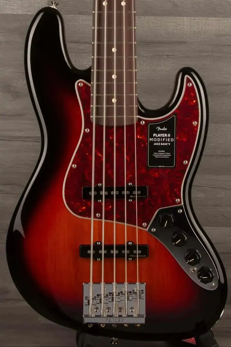 Red electric bass guitar with a black pickguard on a wooden background