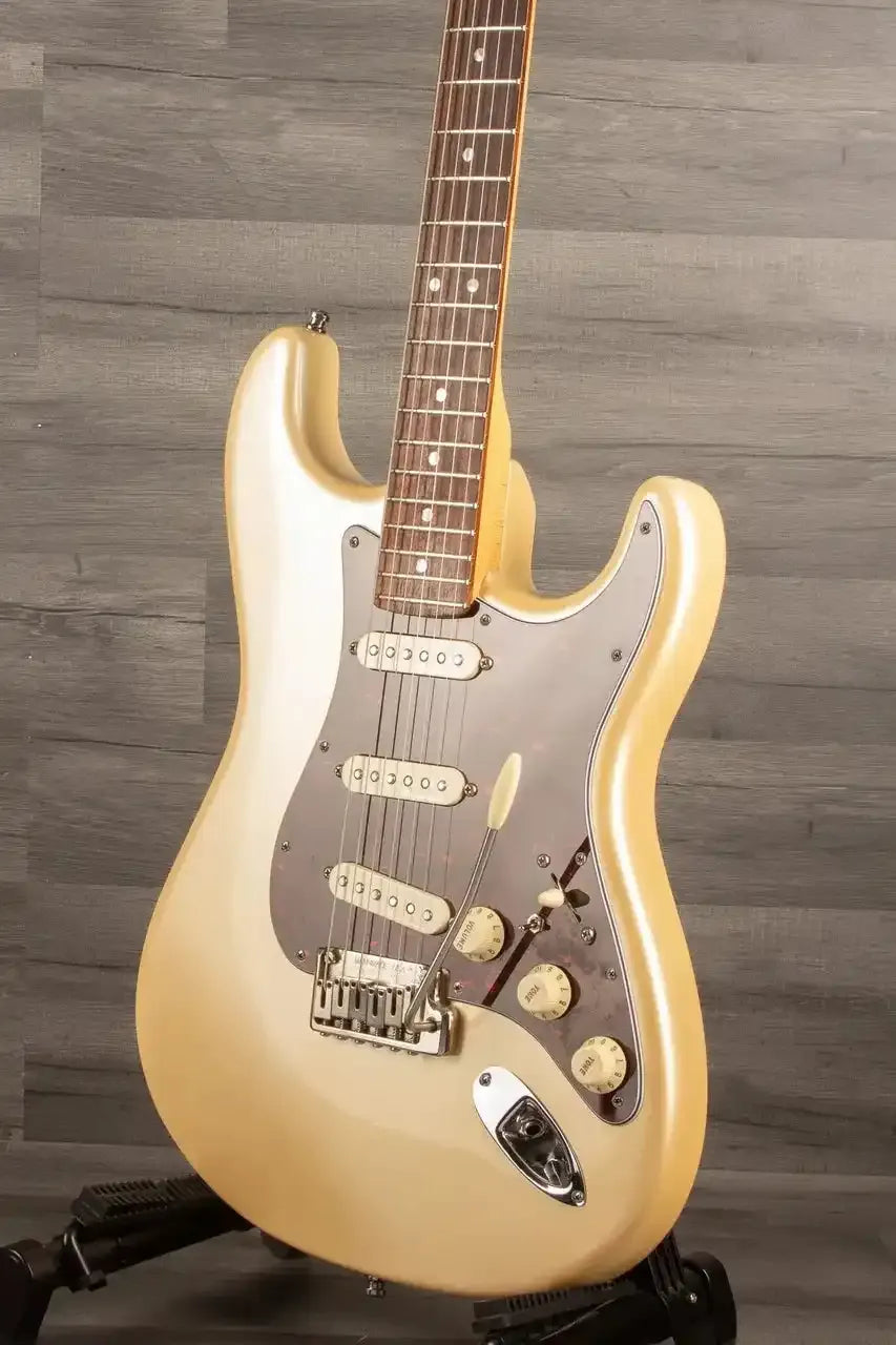 Beige electric guitar on a stand against a wooden background