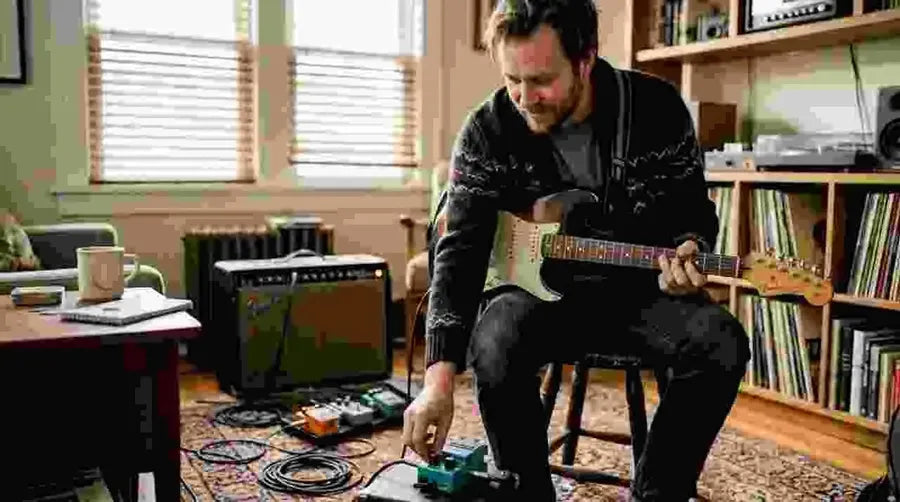 Guitarist adjusts chorus pedal in home studio
