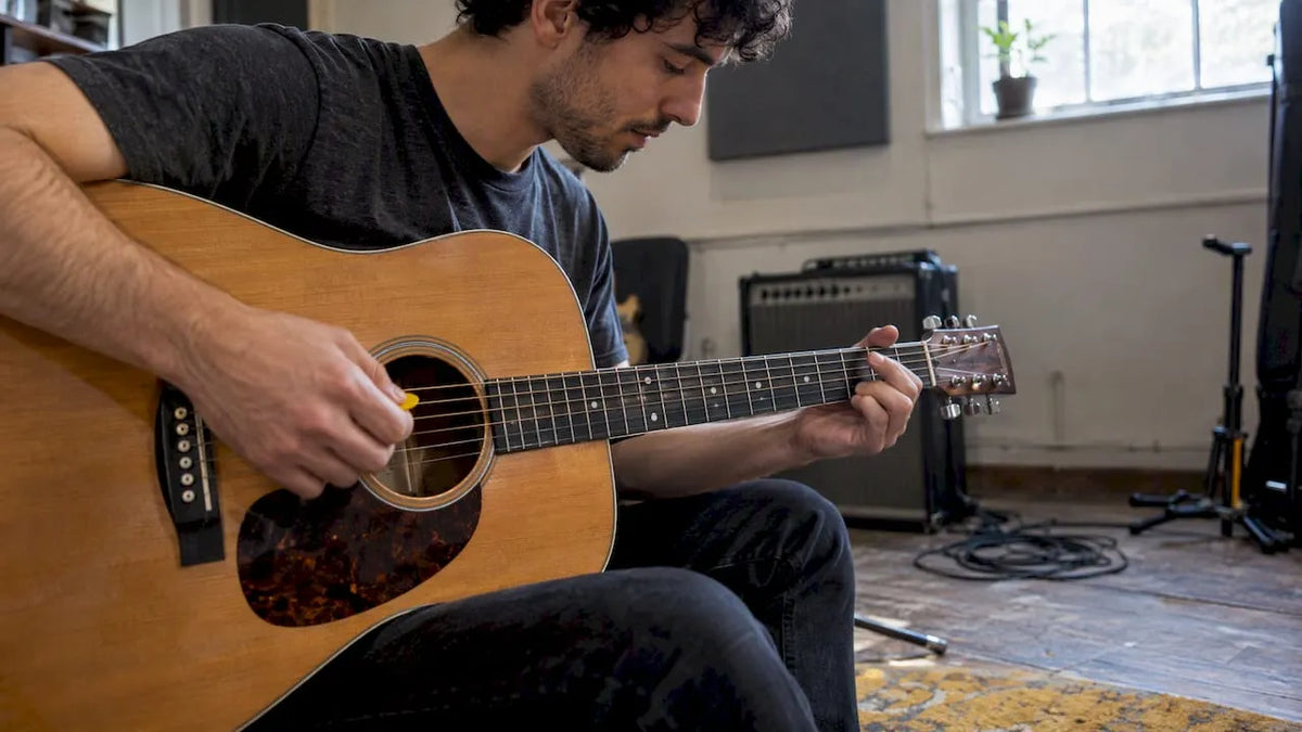 Guitarist plucking open strings in a rehearsal room
