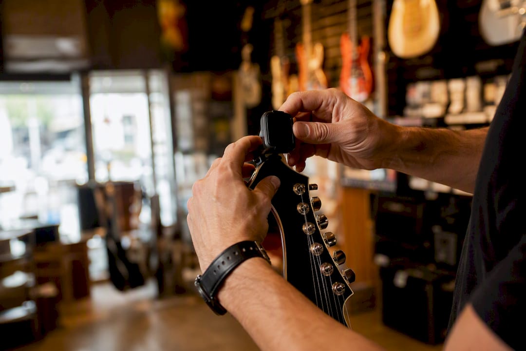 Hands clipping tuner on guitar headstock
