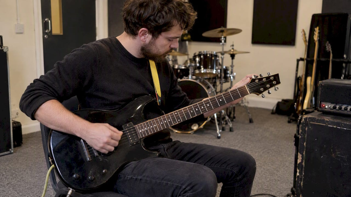 Guitarist checking an electric guitar’s tuning