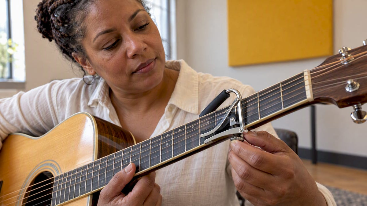 Guitarist positioning a capo behind a fret