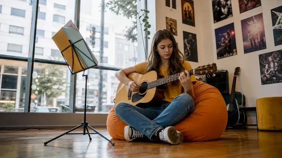 Teenage girl practicing acoustic guitar at home