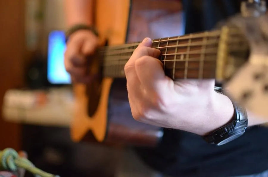 Hands shaping guitar neck in workshop