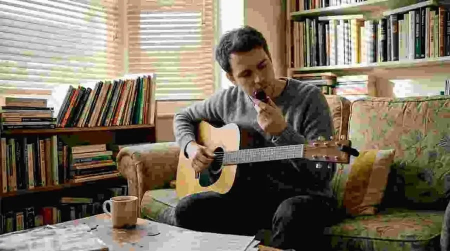 Guitarist tuning acoustic guitar in living room