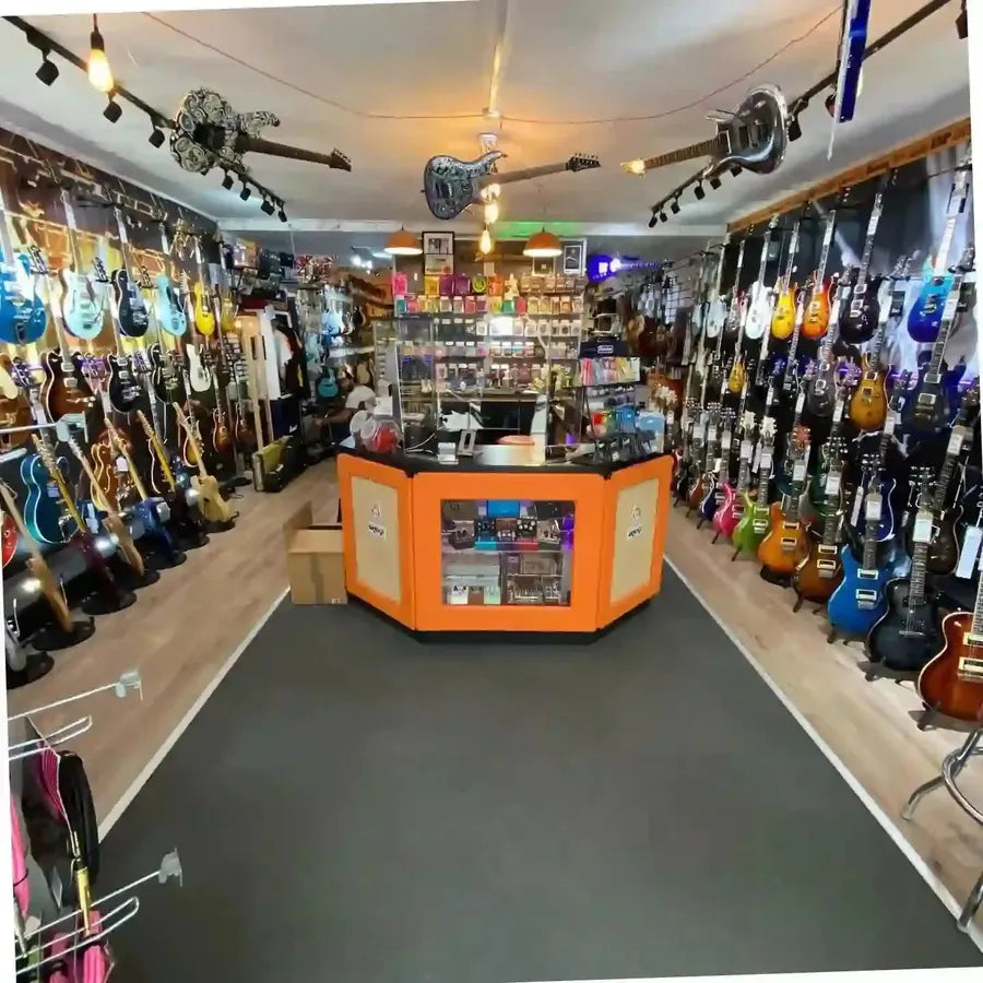 Guitar store interior with multiple guitars displayed and a central counter.
