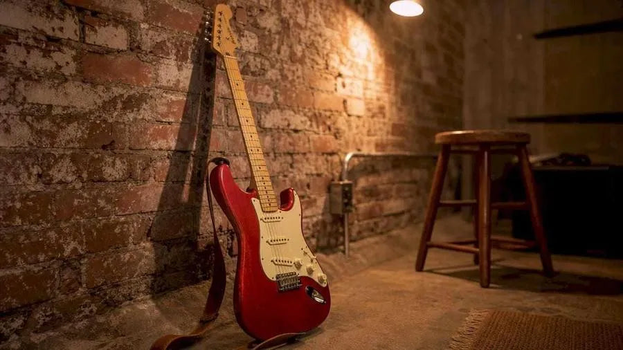 Fender Stratocaster guitar on wooden floor with studio amp