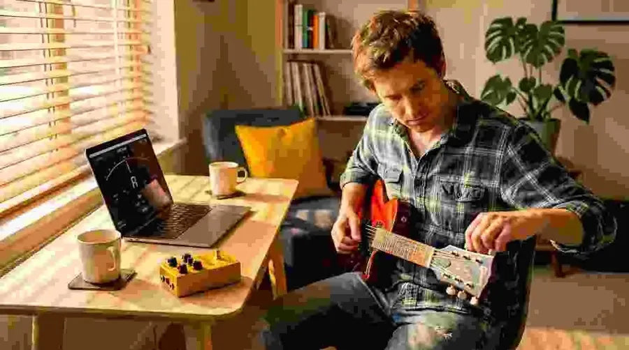 Guitarist tuning electric guitar at home