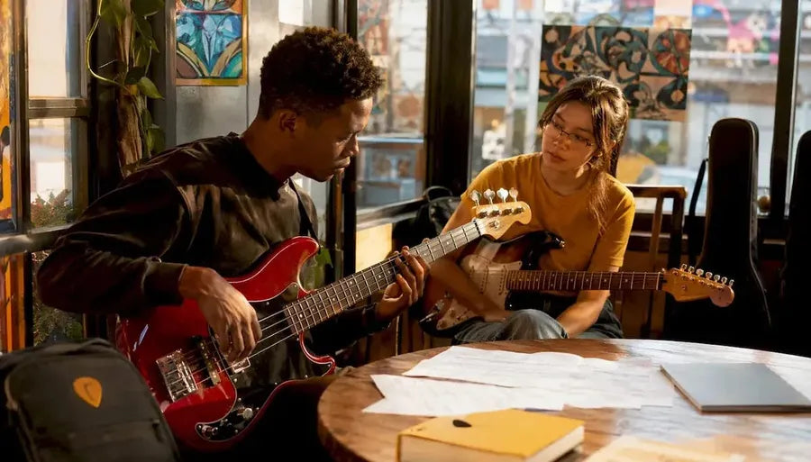 Two people comparing bass and electric guitars