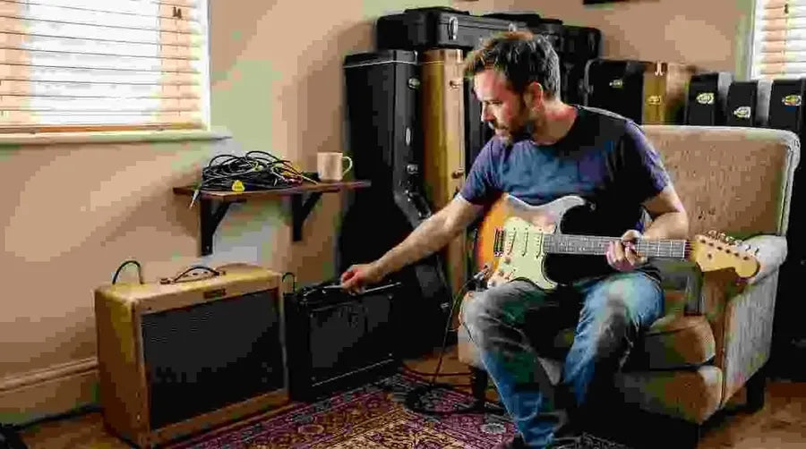 Guitarist comparing tube and digital amps in home studio