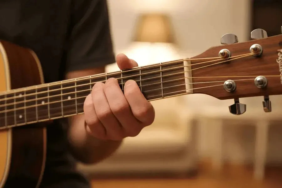 A close-up of a person playing a best acoustic guitar for beginners in a cozy indoor setting.