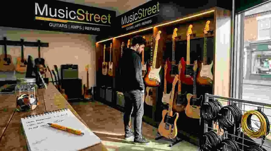 Customer browsing guitars in a sunlit shop