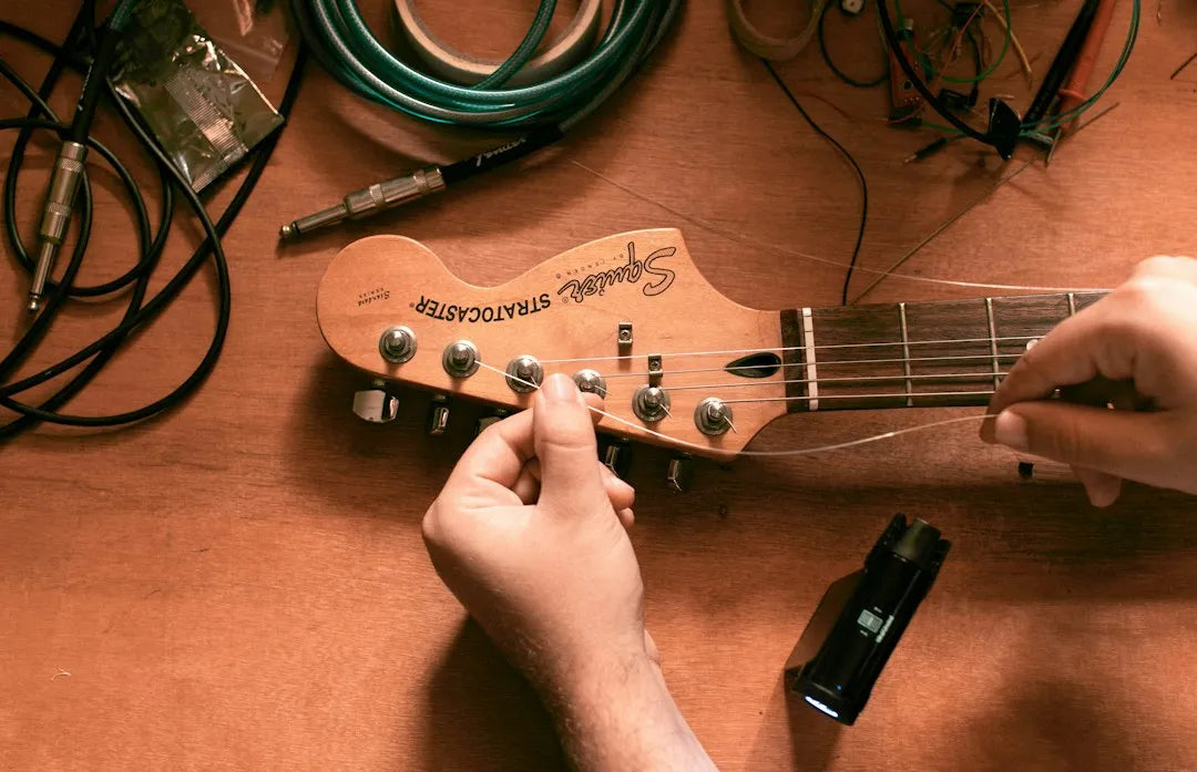 Technician restringing a guitar with locking tuners