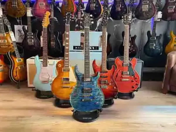Six electric guitars displayed in a music store, featuring various colors and styles.