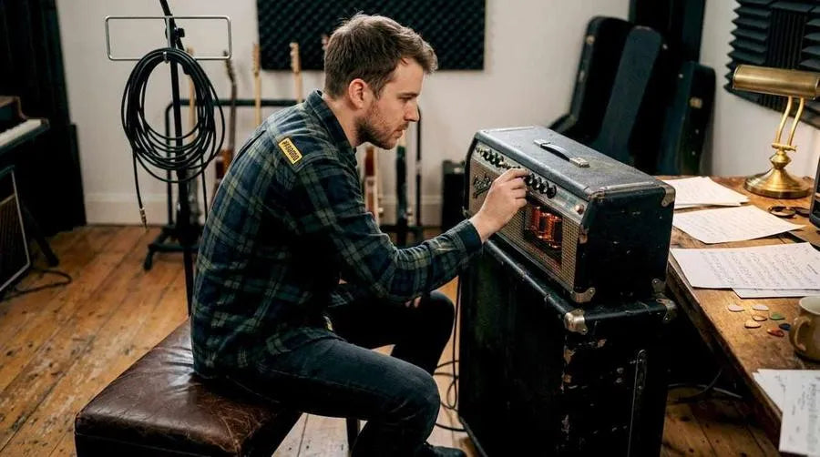 Guitarist adjusting tube amplifier in home studio