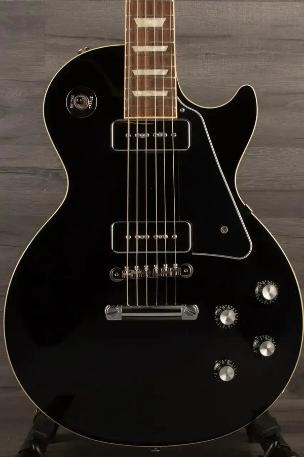 Black electric guitar on a wooden stand against a wooden background