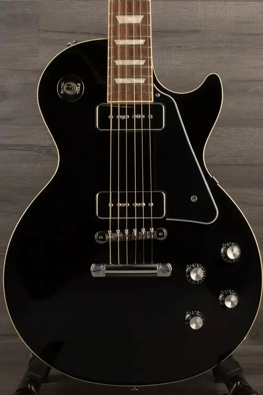 Black electric guitar on a wooden stand against a wooden background