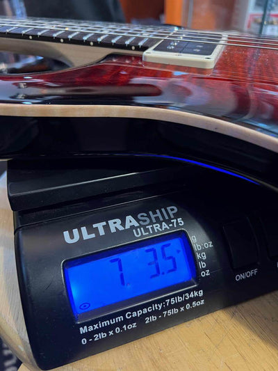 USED - PRS CE24 Semi Hollow - Fire Red on scale showing 7.35 lbs, highlighting its weight for buyers.