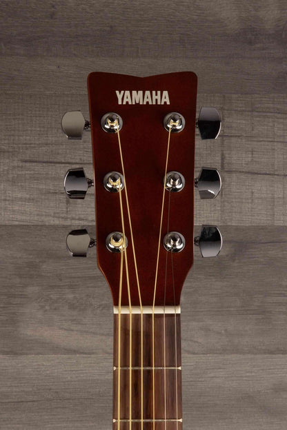 Yamaha FS400 Natural Satin acoustic guitar headstock with tuning pegs and strings against a wooden background.