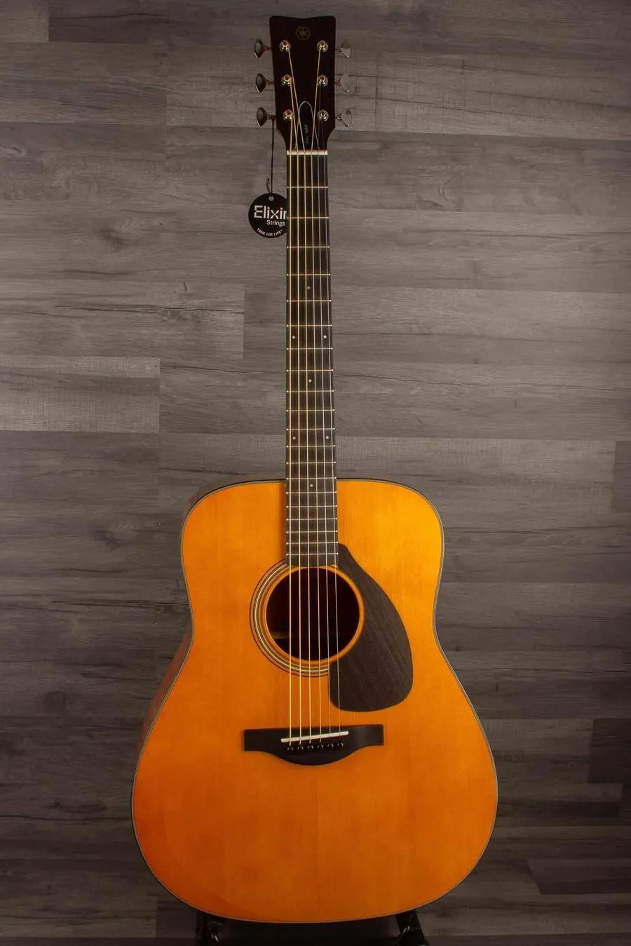 Yamaha FG5G - Acoustic Guitar displayed against a wooden backdrop, showcasing its solid sitka spruce top and African mahogany body.