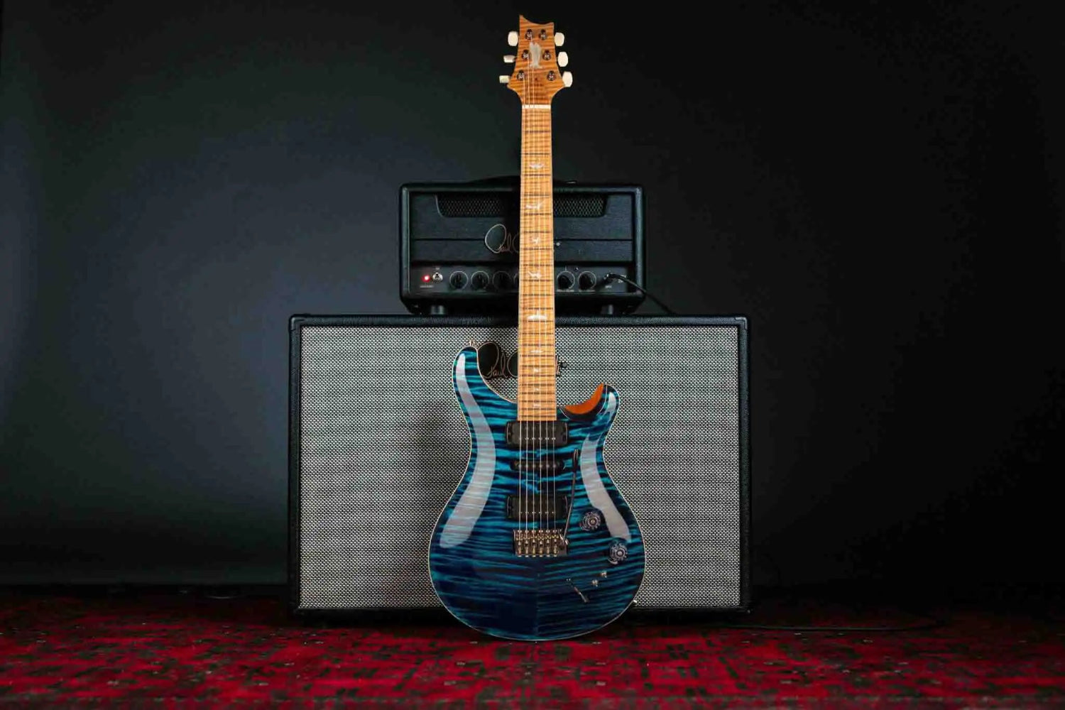 Stunning blue electric guitar on an amp, showcasing its sleek design against a dark background.