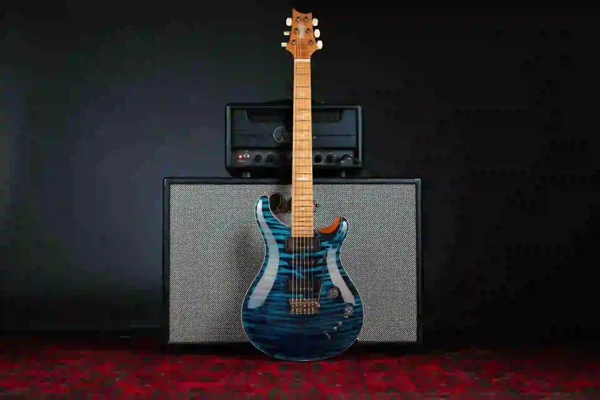 Stunning blue electric guitar on an amp, showcasing its sleek design against a dark background.