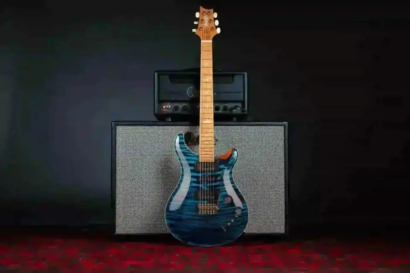 Blue electric guitar with a amplifier on a dark background