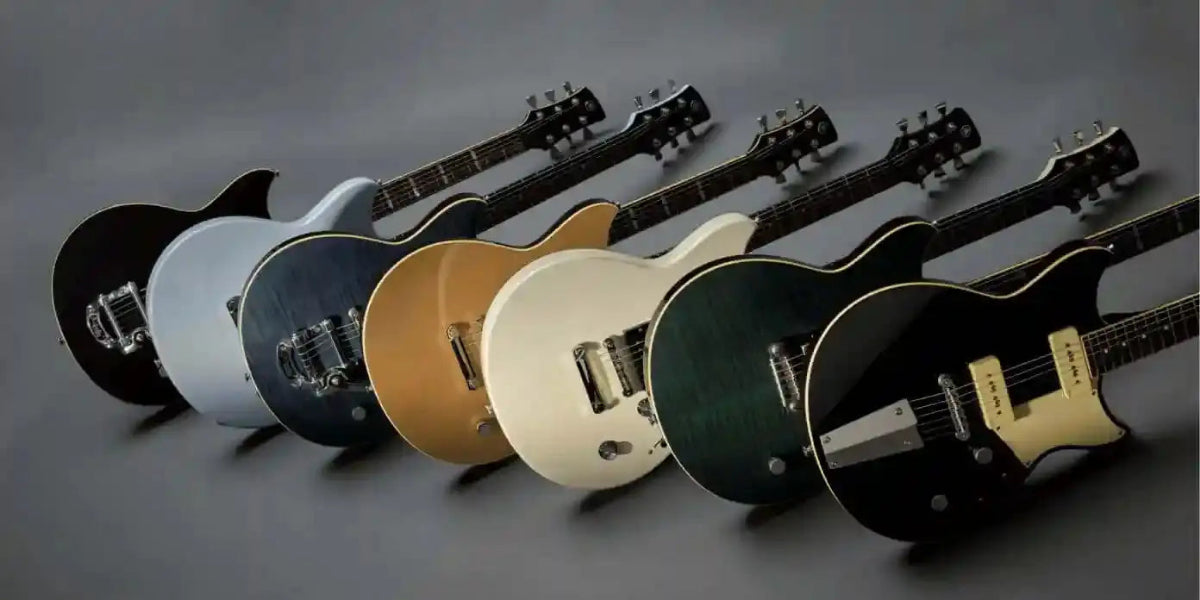 Collection of six electric guitars in various colors lined up against a gray backdrop, showcasing their unique designs.
