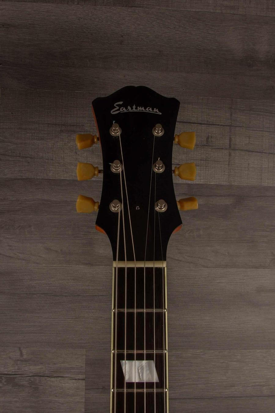 USED - Eastman T64/V Antique Varnish guitar headstock with tuning pegs and logo on wood background.