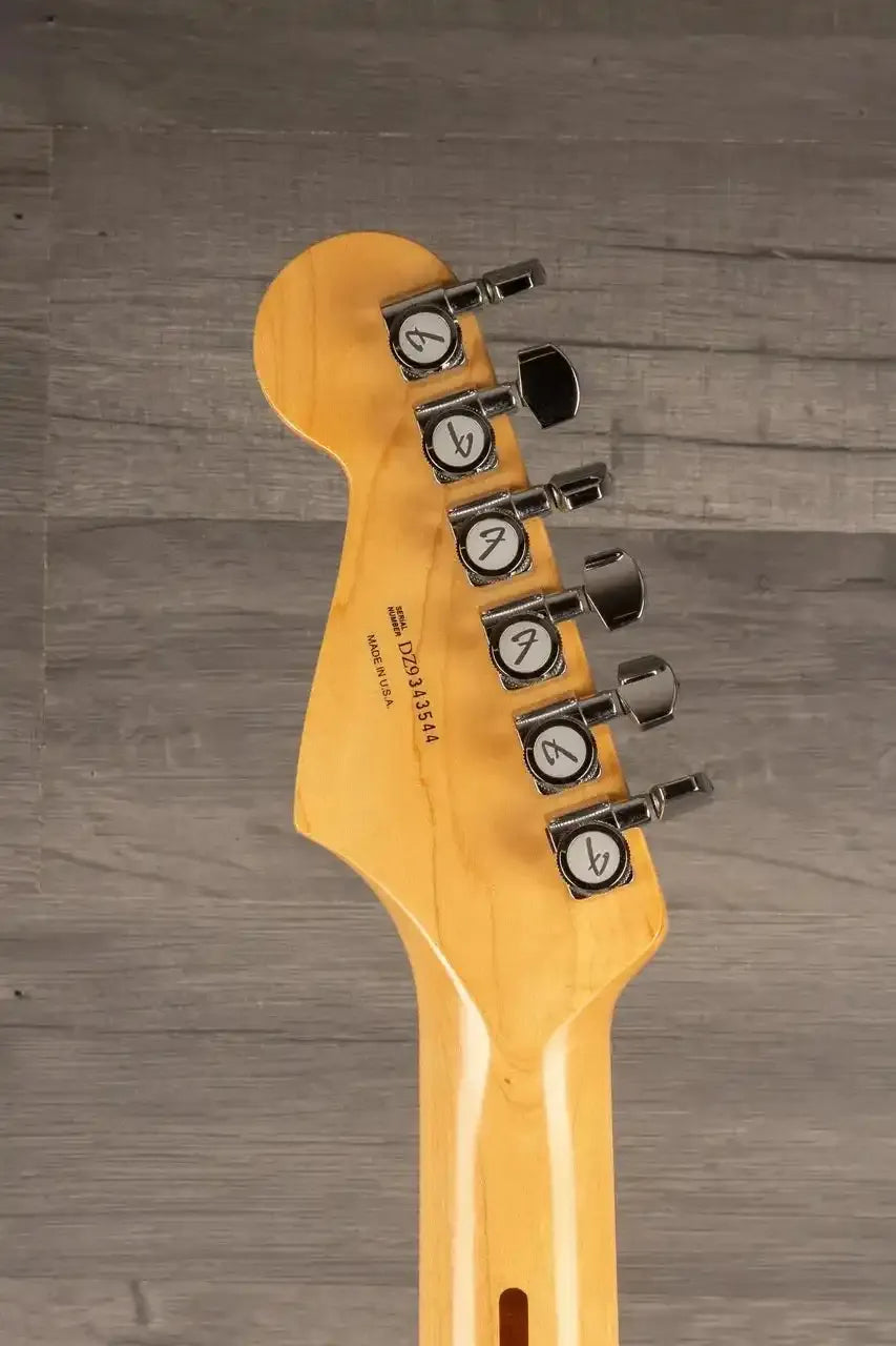 Guitar headstock with tuning pegs on a wooden surface