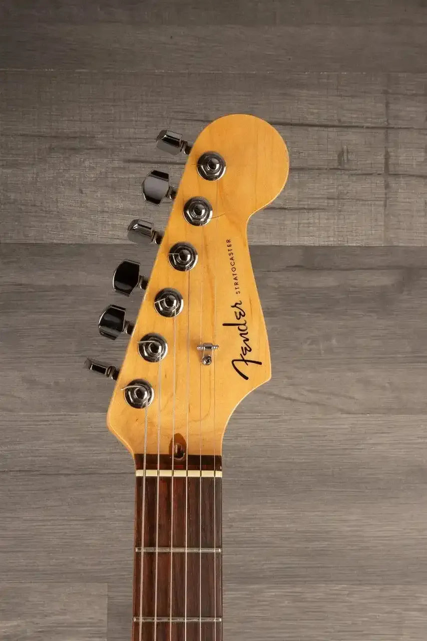 Guitar headstock with Fender logo on a wooden surface