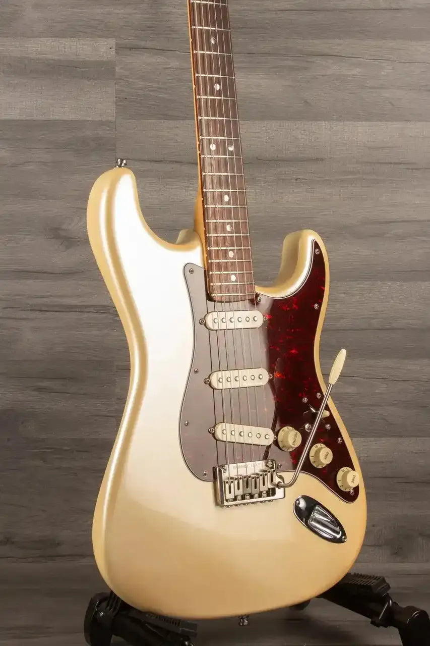 Beige electric guitar on a wooden stand against a wooden background